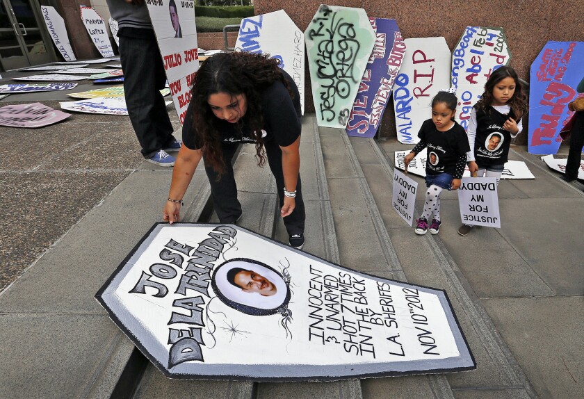 LOS ANGELES, CA APRIL 7, 2015 -- Rosanna De la Trinidad, with her two daughters, places a marker at the L.A. County Hall of Administration on Tuesday in memory of her husband. Supervisors approved a $5.3-million settlement for the family.