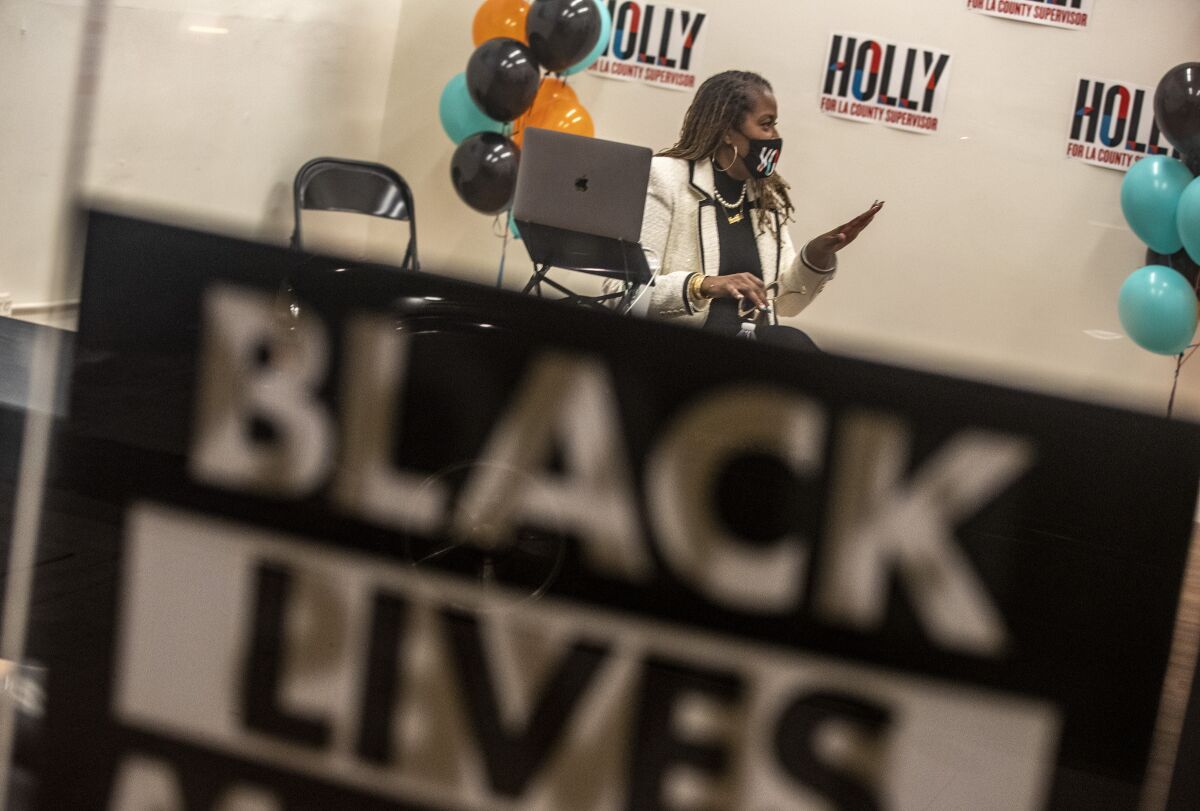 L.A. County Supervisor Holly Mitchell behind a Black Lives Matter poster