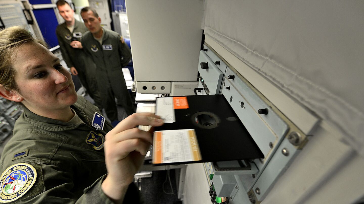 Air Force Lt. Katie Grimley slides a floppy disk into a 1960s-era communication module in a launch control center. The computers use 8-inch disks that have long been obsolete; some spare parts for the complex have been pulled from military museums.