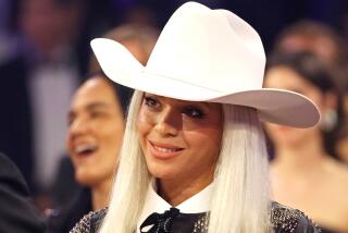 Beyoncé with long platinum hair, wearing a wide-brimmed hat, smiling and tilting her head at an angle
