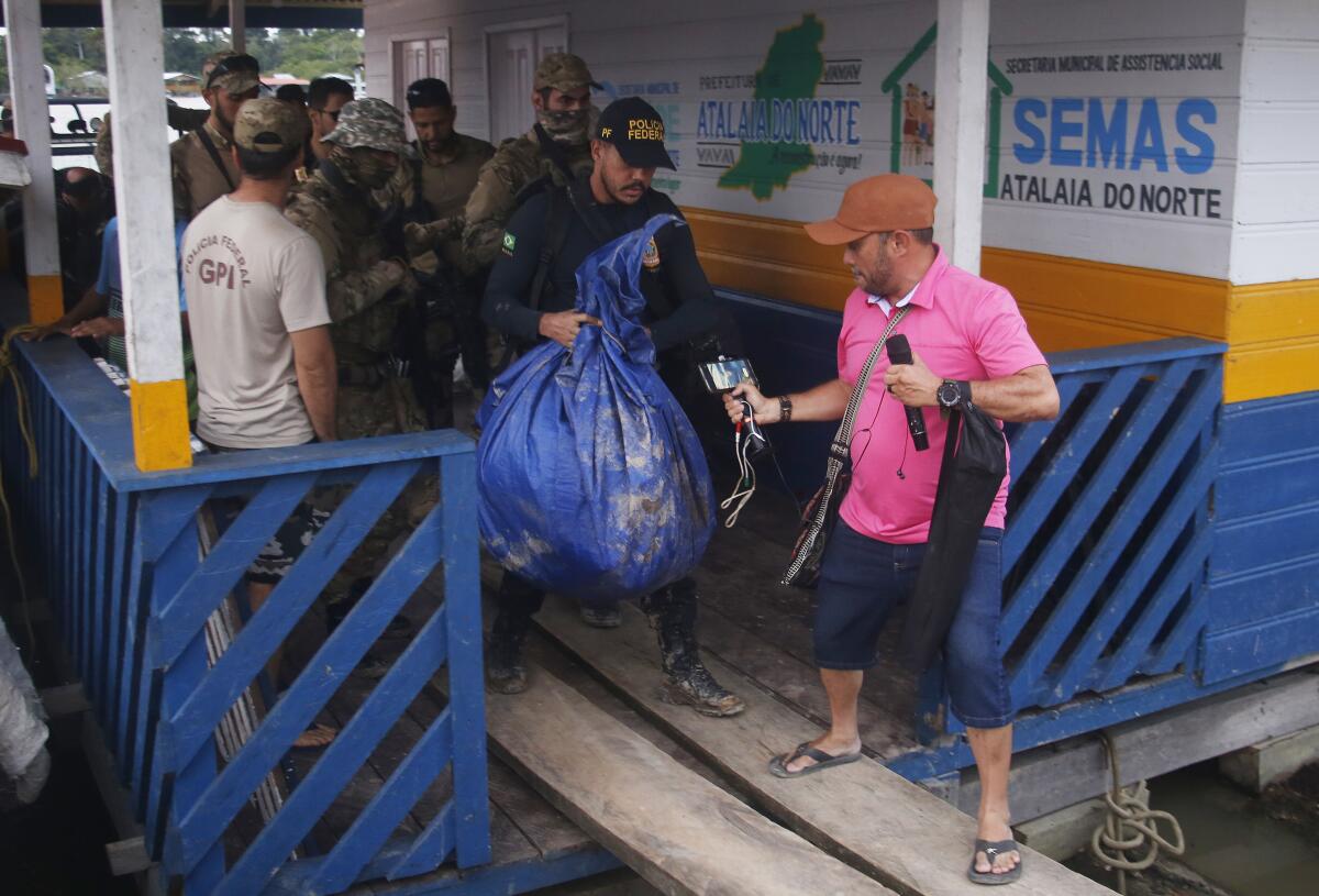 Federal police officers arrive at the pier with items found during a search for Indigenous expert Bruno Pereira and freelance British journalist Dom Phillips in Atalaia do Norte, Amazonas state, Brazil, Sunday, June 12, 2022. Divers from Brazil's firefighters corps found a backpack and laptop Sunday in the remote Amazon area where Pereira and Phillips went missing a week ago, firefighters said. (AP Photo/Edmar Barros)