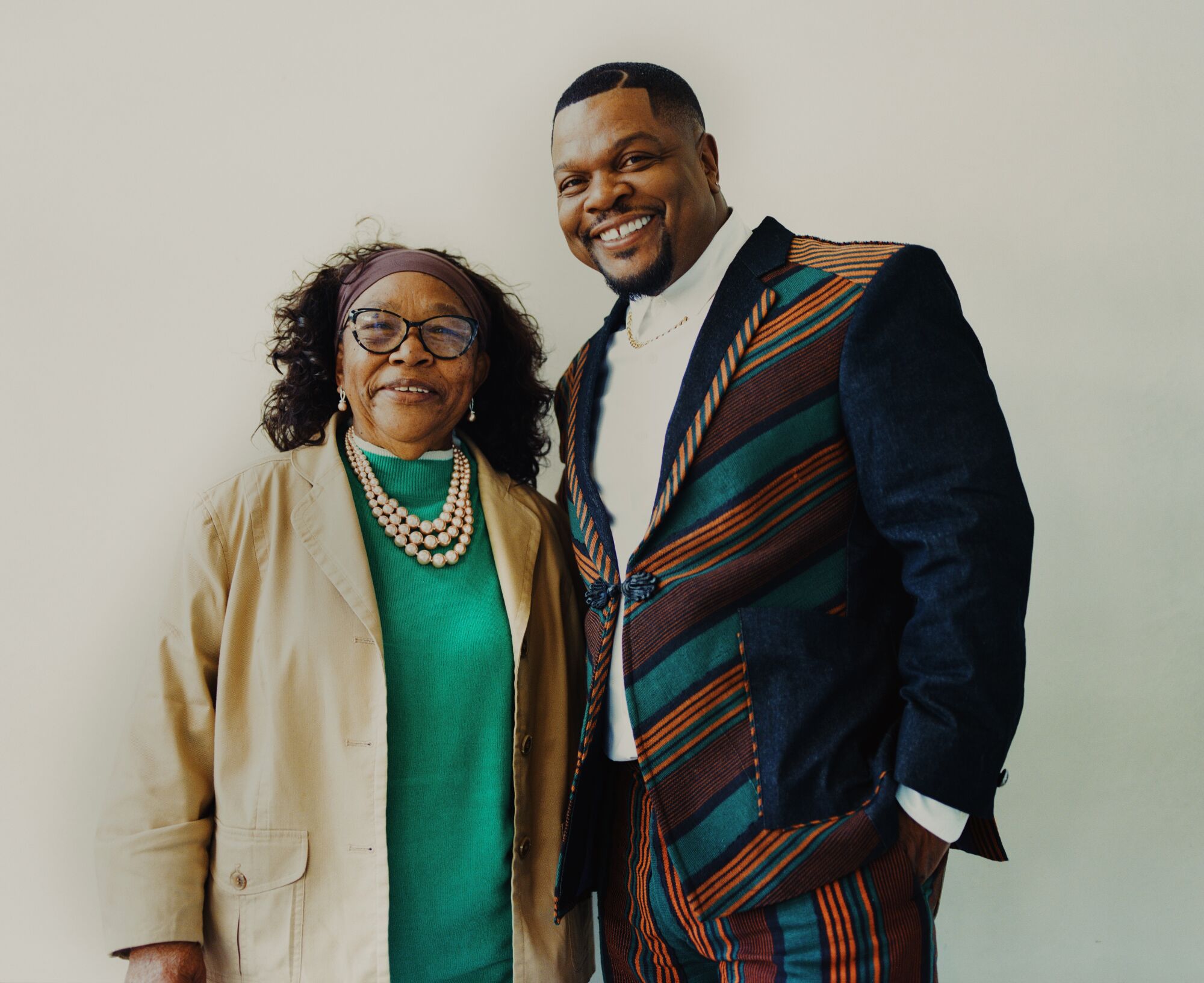 A man and his mother stand side by side, smiling.