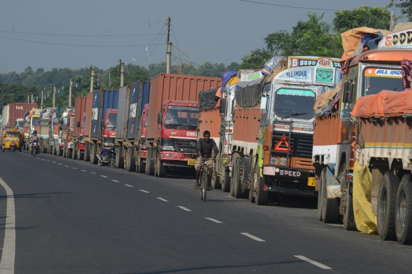 An Indian man cycles past parked Indian trucks carrying goods to Nepal near the India-Nepal border at Panitanki on Tuesday.