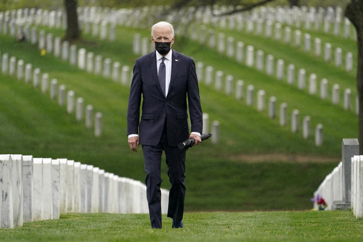 Biden walks among headstones at a cemetery.