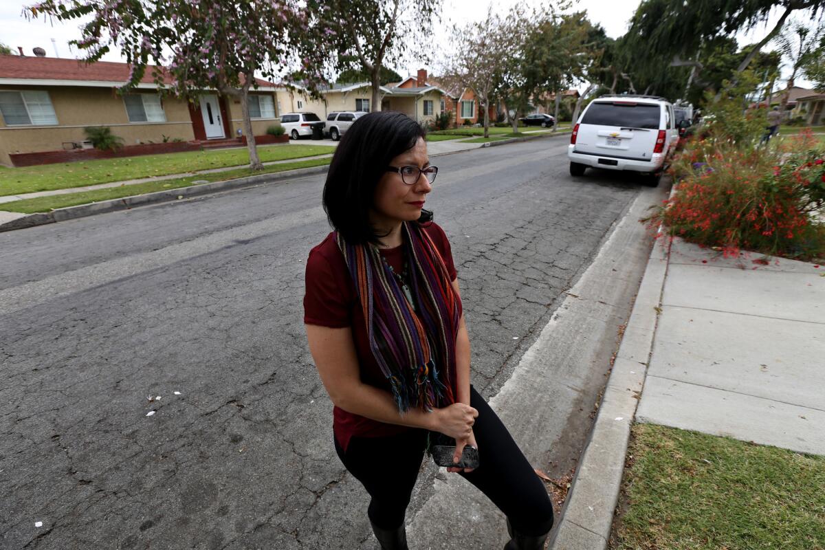 Beatriz Paez, 34, holding a broken phone on the 10400 block of San Juan Avenue in South Gate, where her cellphone was snatched and tossed during a reported federal law enforcement operation she had been recording.