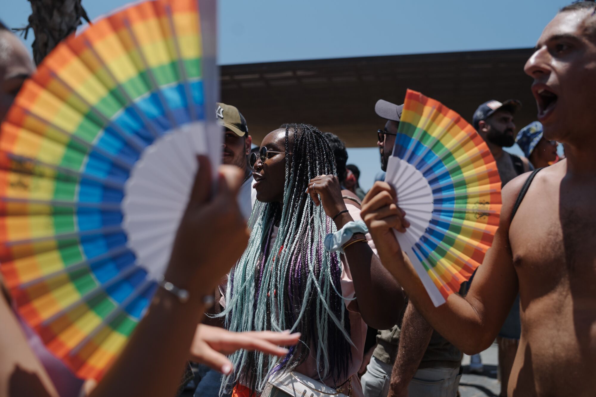 A woman is seen between two rainbow-colored fans. 