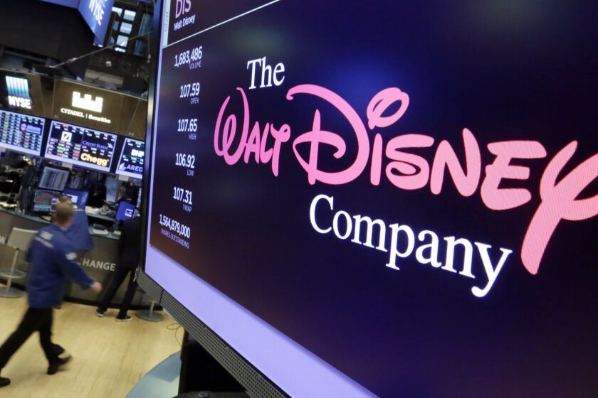 FILE - In this Aug. 8, 2017, file photo, The Walt Disney Co. logo appears on a screen above the floor of the New York Stock Exchange. Disney closed its $71 billion acquisition of Foxs entertainment assets on Wednesday, March 20, 2019, more than a year after the mega merger was proposed. Disney gets far ranging properties ranging from Foxs film studios, including Avatar and X-Men, to its TV productions such as The Simpsons and networks including National Geographic. (AP Photo/Richard Drew, File)