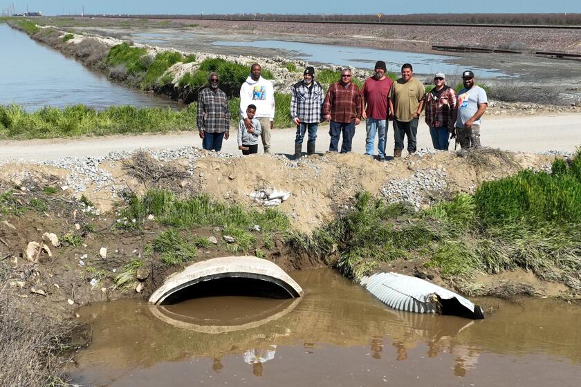 Allensworth, CA, Saturday, March 18, 2023 - Allensworth residents pose for a photo next to a levy they worked to fortify instead of waiting for government agencies to prevent floodwaters from inundating their community. (Robert Gauthier/Los Angeles Times)