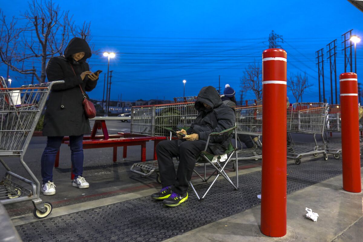 A couple waits in line at Costco in Hawthorne well before it opens.