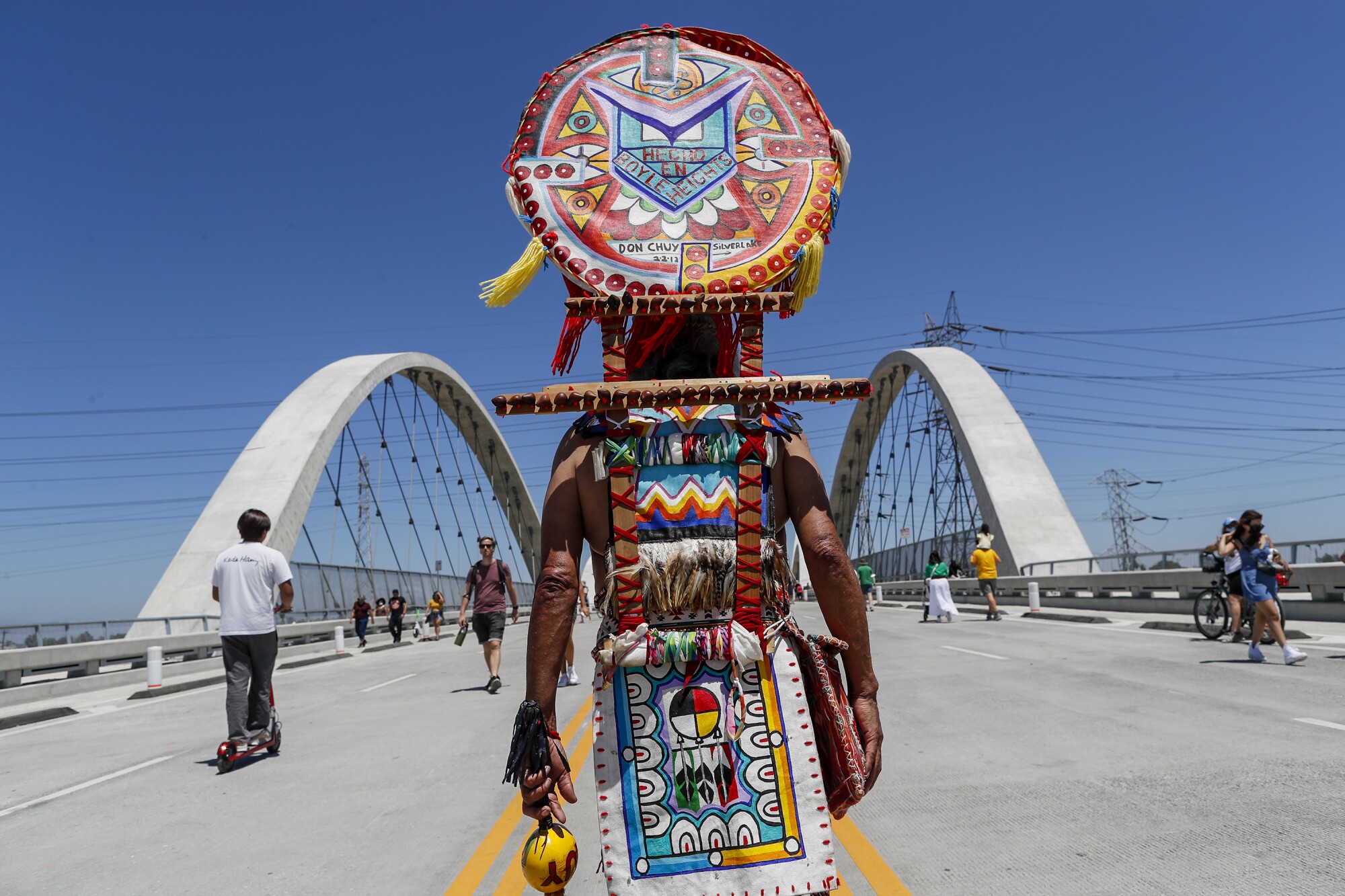 A man wearing Aztec garb walks along the 6th Street Viaduct.