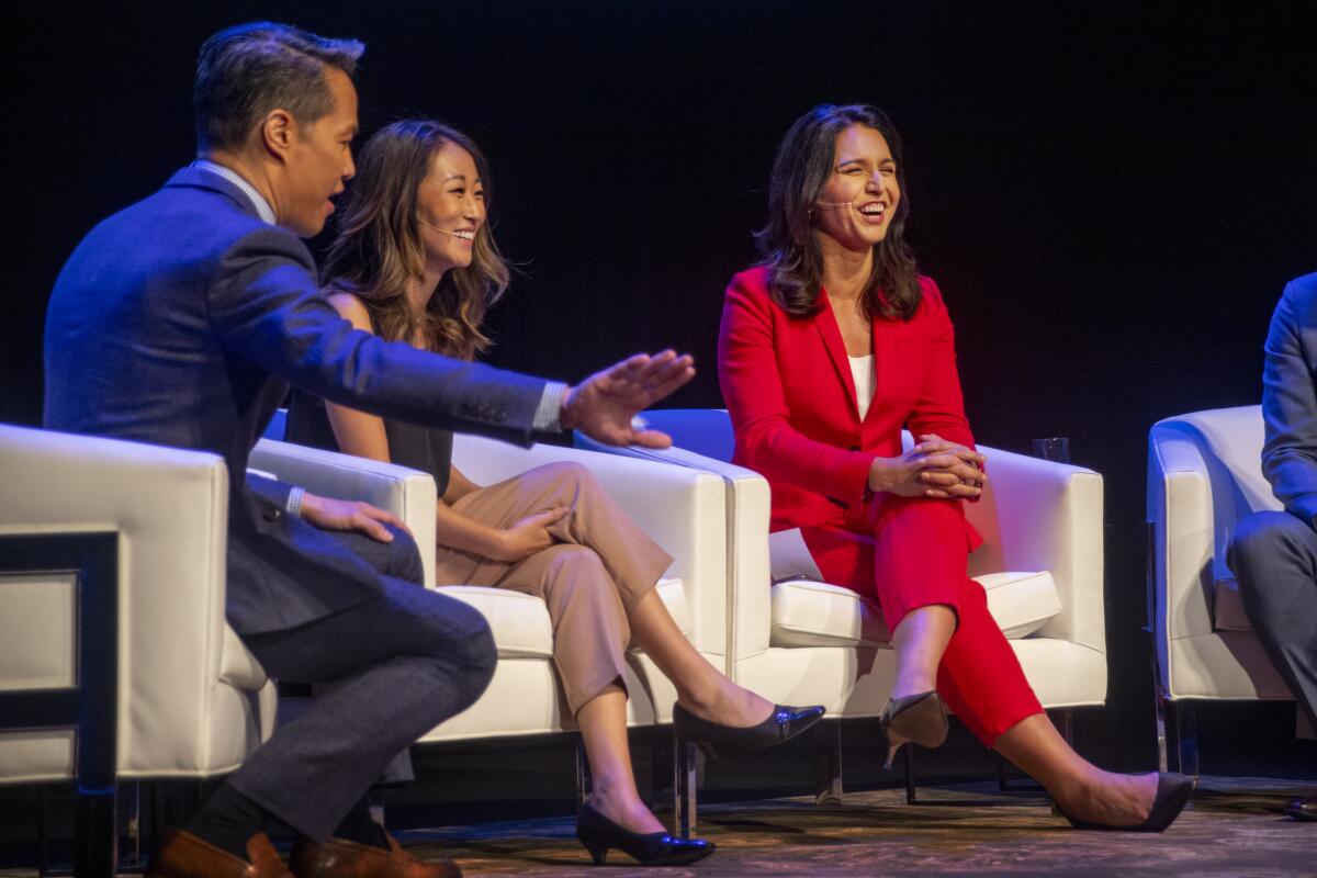 Rep. Tulsi Gabbard (D-Hawaii), in red, speaks Sunday with panelists Richard Lee and Esther Lee at a forum for Democratic presidential candidates at the Segerstrom Center for the Arts in Costa Mesa.