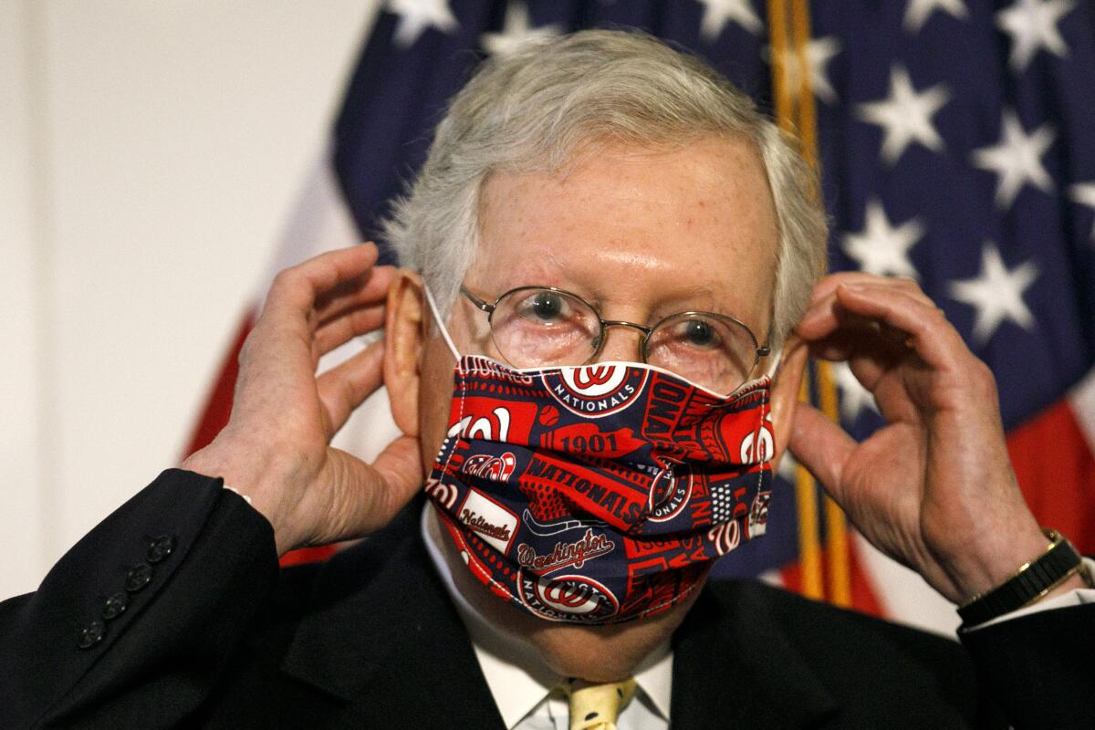 Senate Majority Leader Mitch McConnell replaces his face mask after speaking at a Capitol Hill news conference in the summer