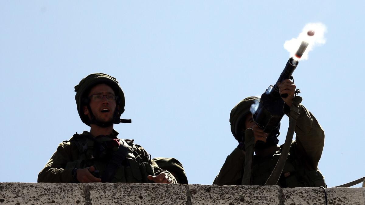 Israeli army soldiers shoot tear gas grenades during clashes with Palestinian stone throwers in the West Bank city of Hebron on Saturday.