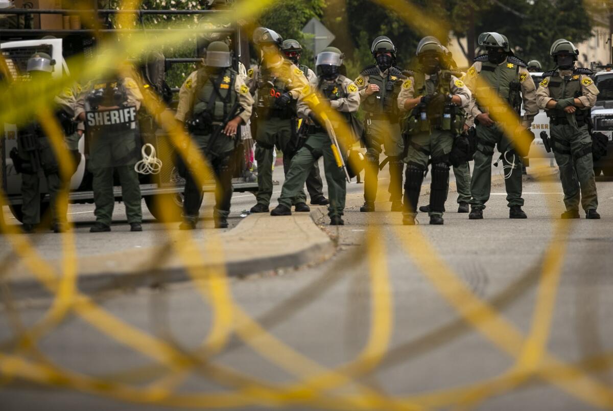 L.A. Sheriff's Deputies in riot gear watch protesters by the South L.A. Sheriff's station during a protest for Dijon Kizzee.