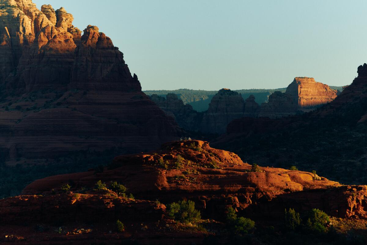 The surrounding views from a rock formation with people sitting on an adjacent mountain top