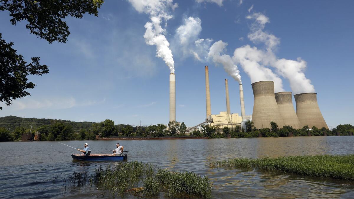 Fishermen drift by the coal-powered John E. Amos Power Plant in Poca, W.Va. Democratic congressional candidate Richard Ojeda is fighting for the continuation of pension plans for coal miners in his state.