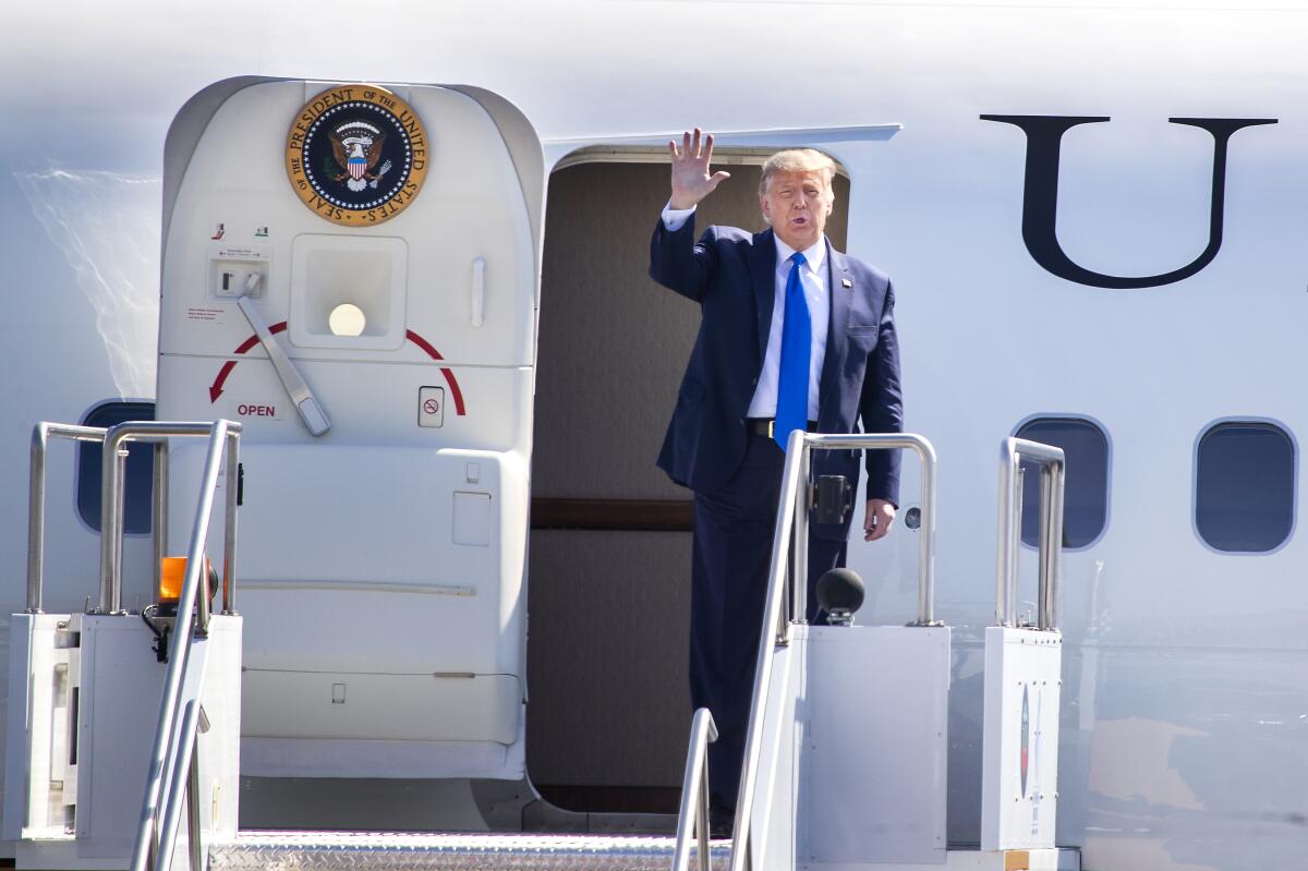 President Donald Trump waves to supporters as he arrives on Air Force One at John Wayne Airport in Santa Ana on Sunday.