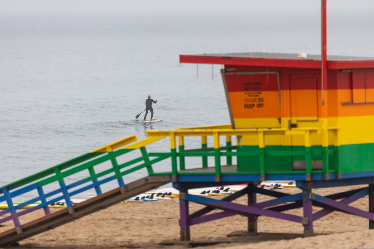  A paddleboarder is seen on a foggy morning in the waves off Hermosa Beach