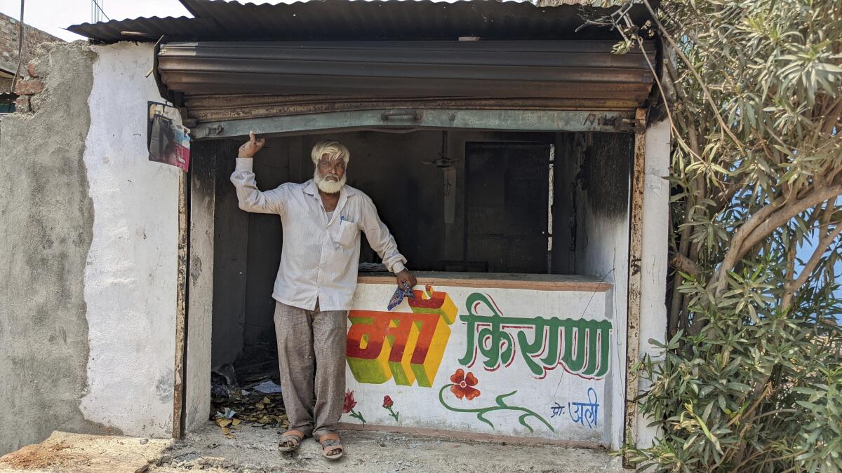 A man stands in a vandalized storefront.