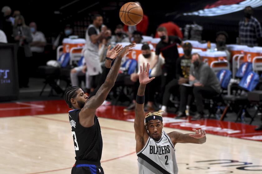 Los Angeles Clippers guard Paul George, left, hits a shot over Portland Trail Blazers forward Rondae Hollis-Jefferson, right, during the first half of an NBA basketball game in Portland, Ore., Tuesday, April 20, 2021. (AP Photo/Steve Dykes)