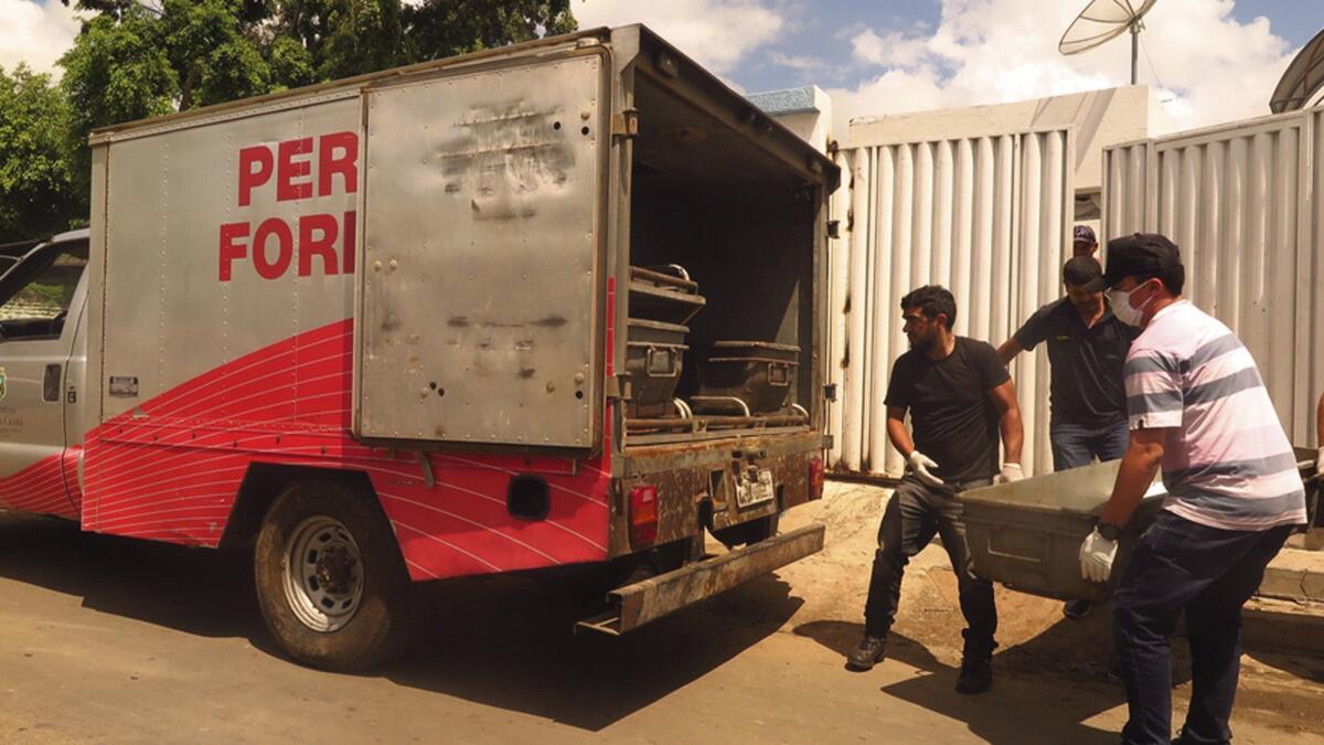 Forensic officers load the body of a victim killed in an attempted bank robbery at an entrance of a municipal hospital in Milagres, in Brazil's state of Ceara on Friday.