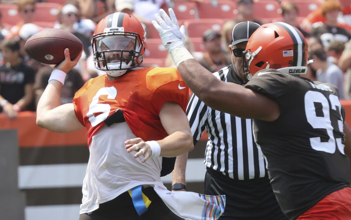 Cleveland Browns quarterback Baker Mayfield, left, throws a pass away under pressure from defensive tackle Tommy Togiai during an Orange and Brown NFL football practice in Cleveland, Sunday, Aug. 8, 2021. (John Kuntz/The Plain Dealer via AP)