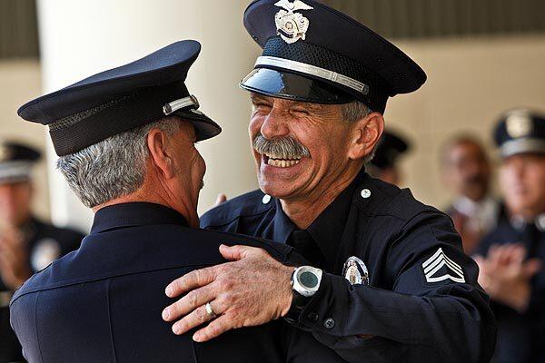 LAPD Deputy Chief Richard A. Roupoli, left, on Friday gets a hug from retiring SWAT supervisor Sgt. Steve Gomez at department headquarters in downtown Los Angeles. Gomez was the last SWAT officer involved in the infamous 1997 North Hollywood bank shootout to retire. Two bank robbers died and 11 officers and seven civilians were wounded in the heist.