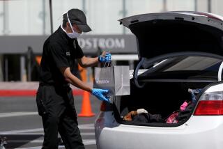 COSTA MESA, CA -- MAY 15: A Nordstrom employee delivers merchandise to a customer waiting in their vehicle at curbside pickup outside Nordstrom at South Coast Plaza on Friday, May 15, 2020, in Costa Mesa, CA. South Coast Plaza has joined the list of outlets offering contact-free pickup for customers amid the coronavirus pandemic. Customers remain in their auto while their items are put in their car's trunk. (Gary Coronado / Los Angeles Times)