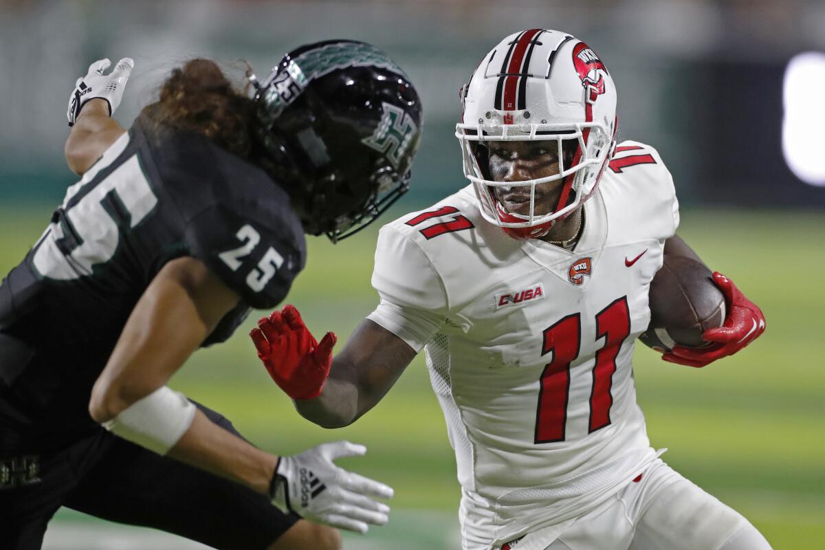 Western Kentucky wide receiver Malachi Corley (11) prepares to fend off Hawaii defensive back Matagi Thompson (25) during the first half of an NCAA college football game Saturday, Sept. 3, 2022, in Honolulu. (AP Photo/Marco Garcia)