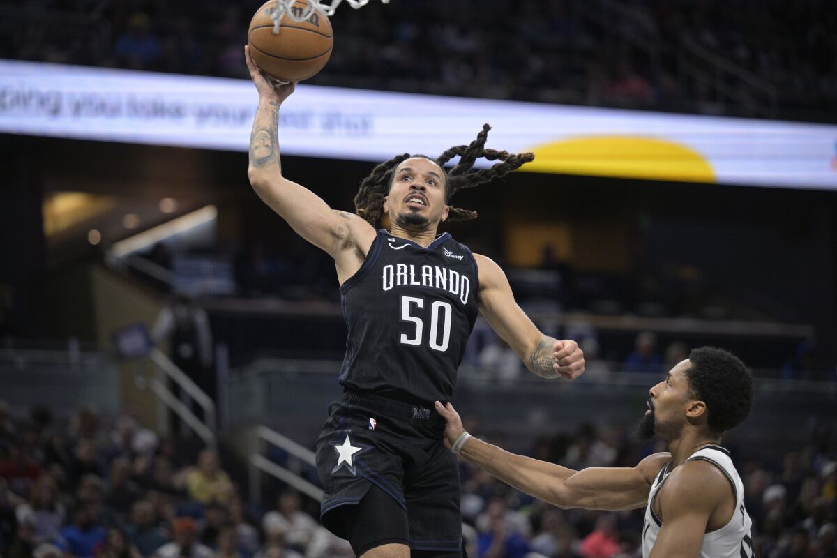 Orlando Magic guard Cole Anthony (50) goes up to shoot in front of Brooklyn Nets guard Spencer Dinwiddie during the second half of an NBA basketball game, Sunday, March 26, 2023, in Orlando, Fla. (AP Photo/Phelan M. Ebenhack)