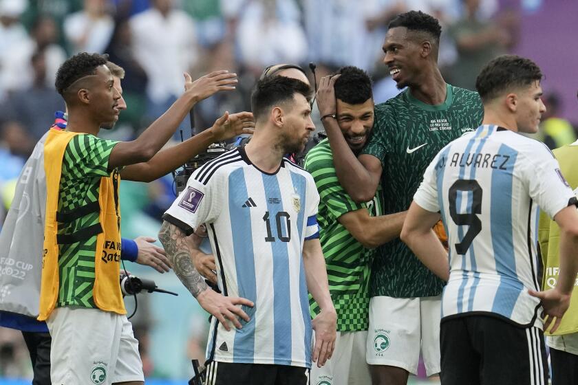 Argentina's Lionel Messi standing beside Saudi Arabia's players celebrating after winning the World Cup group C soccer match