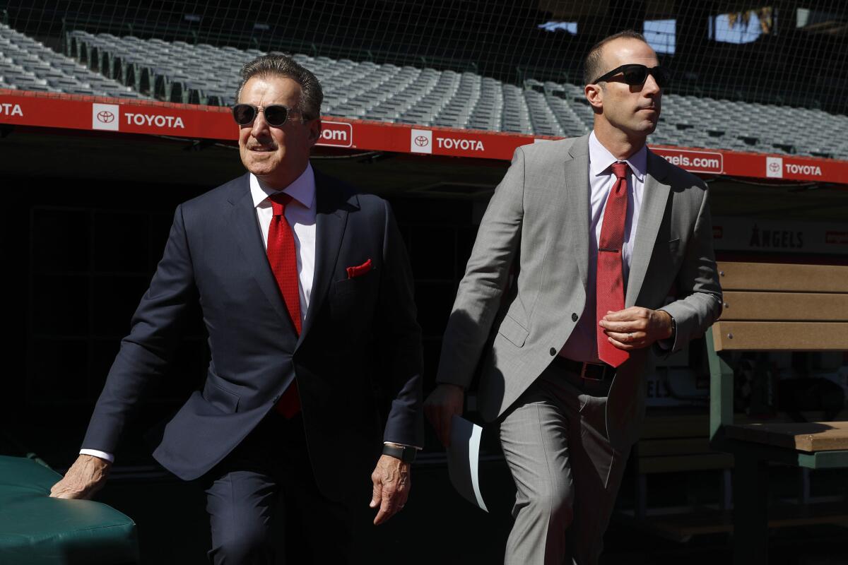 Angels owner Arte Moreno, left, and general manager Billy Eppler make their way onto the field at Angel Stadium to introduce Joe Madden as the team's new manager Thursday.