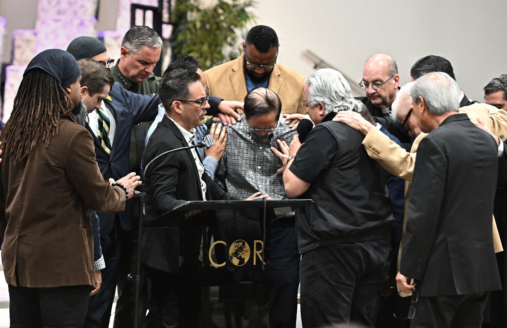 Officials pray around former pastor Billy Chang, center, as he tries to hold back his emotions