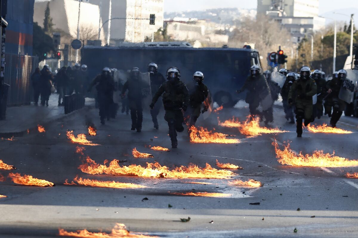Riot policemen run through flames from petrol bombs during a rally in the northern Greek city of Thessaloniki, Greece, on Saturday, Jan. 15, 2022. The rally was the culmination of a week of protests over the New Year's Eve eviction of activists who had occupied a room at the university's Biology department for 34 years and turned violent towards its end, when some of the marchers threw firebombs and rocks at riot police, who responded with stun grenades and tear gas. (AP Photo/Giannis Papanikos)
