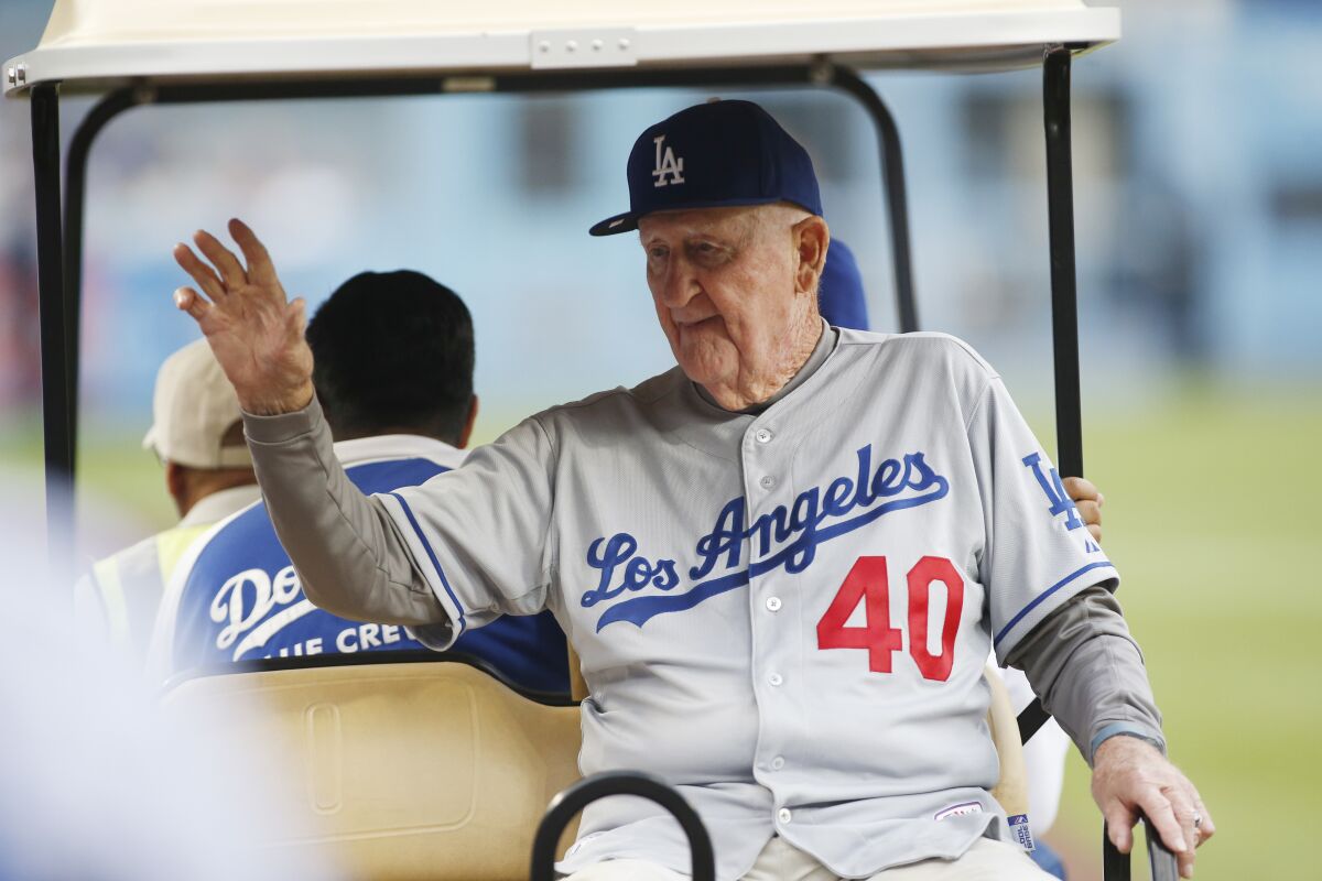 L'ancien lanceur des Dodgers, Roger Craig, fait signe de la main alors qu'il monte dans un chariot avant un match.