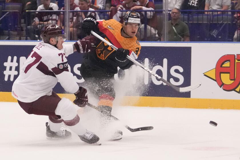 Germany's John Peterka, right, tries to score as Latvia's Kristaps Roberts Zile blocks him during the preliminary round match between Germany and Latvia at the Ice Hockey World Championships in Ostrava, Czech Republic, Wednesday, May 15, 2024. (AP Photo/Darko Vojinovic)