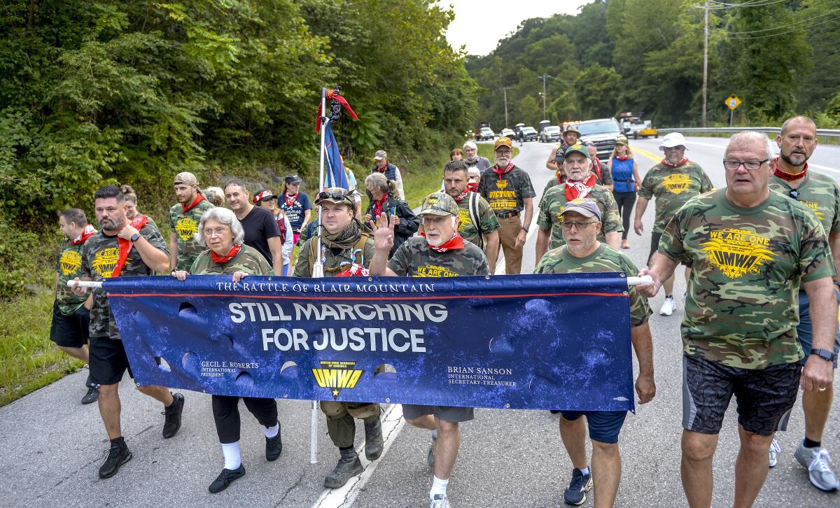 UMWA International President Cecil Roberts, center, with hand raised, leads a chant at the beginning of the march to Blair Mountain on Rt. 94, Friday, Sept., 3, 2021, in Marmet, W.Va. Fed up with poor wages, work and living conditions, thousands of coal miners a century ago marched in an effort to unionize in West Virginia, resulting in a deadly clash and the largest U.S. armed uprising since the Civil War. On Friday, some descendants of those involved joined others in retracing the steps that culminated in the 12-day Battle of Blair Mountain. (Kenny Kemp/Charleston Gazette-Mail via AP)