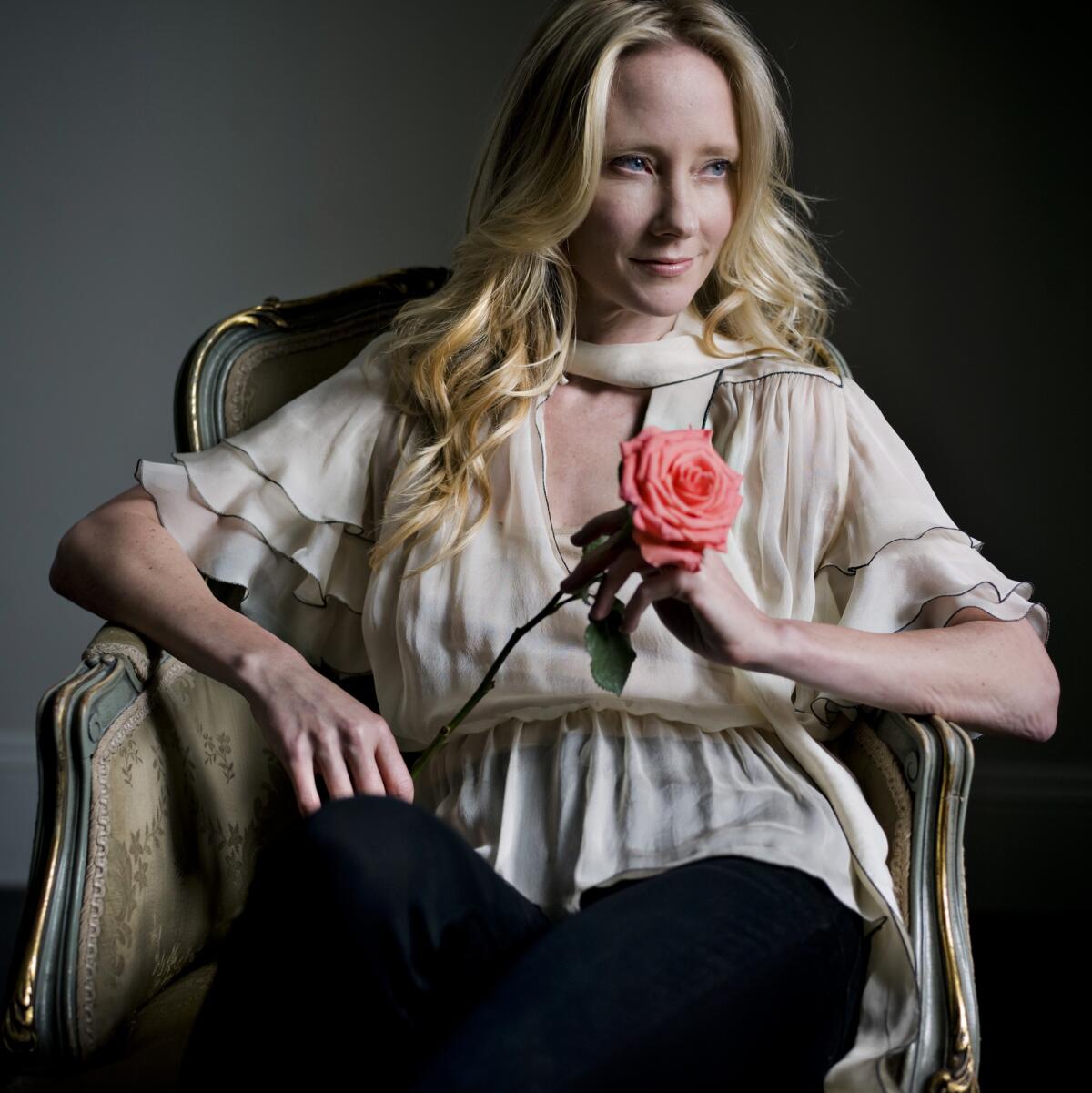 A woman holding a pink rose poses for a portrait