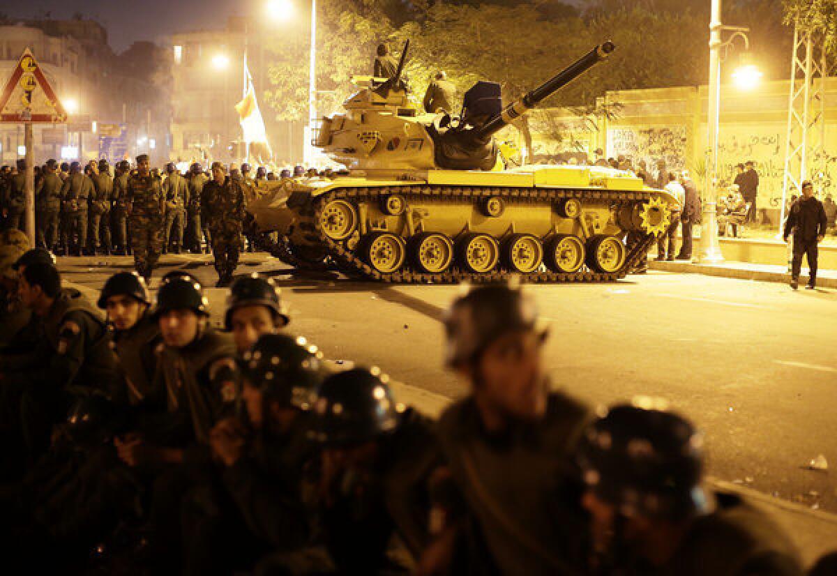 An Egyptian Army tank and troops stand guard against opposition demonstrators outside the presidential palace in Cairo on Tuesday. The military has been empowered to deter unrest ahead of Saturday's vote on a controversial draft constitution that critics say could enshrine Islamic law to the detriment of democracy, human rights and religious freedom.