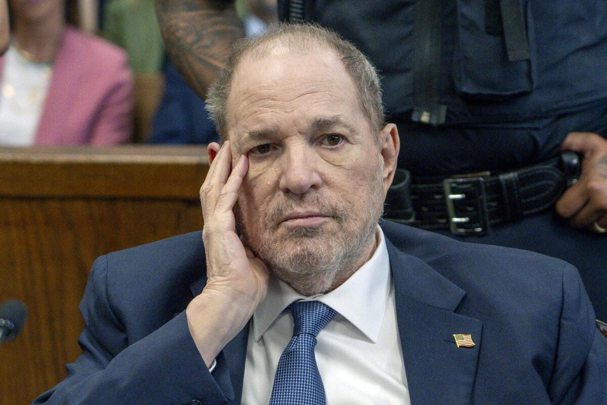 Harvey Weinstein sits in Manhattan criminal court with his head in his hand.