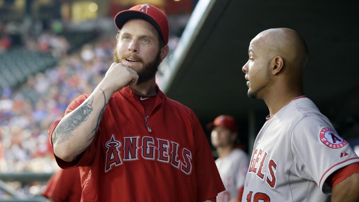 Angels outfielder Josh Hamilton, left, talks with teammate Luis Jimenez in the dugout during Tuesday's win over the Texas Rangers.