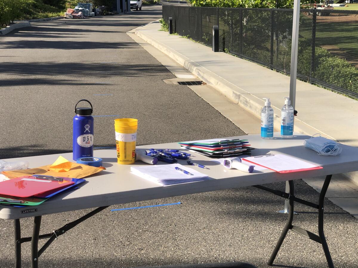 A table with masks, hand sanitizer and thermometers. High school teams are following strict COVID-19 guidelines this summer.