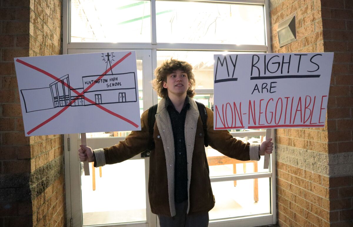 Huntington High School senior Max Nibert holds signs he plans to use during a walkout students are staging at Huntington High School in Huntington, W.Va. on Wednesday, Feb. 9, 2022. The protest follows an evangelistic Christian revival assembly last week that some students at Huntington High were mandated by teachers to attend – a violation of students’ civil rights, Nibert says.