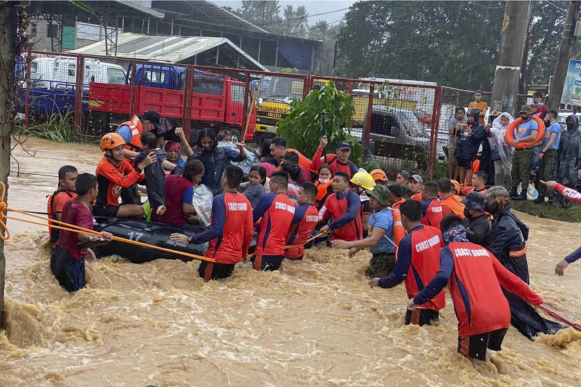 In this handout photo provided by the Philippine Coast Guard, rescuers assist residents over floodwaters caused by Typhoon Rai as they are evacuated to higher ground in Cagayan de Oro City, southern Philippines, Thursday, Dec. 16, 2021. Tens of thousands of people were being evacuated to safety in the southern and central Philippines as Typhoon Rai approached Thursday at a time when authorities were warning the public to avoid crowds after the first infections caused by the omicron strain of the coronavirus were reported in the country, officials said. (Philippine Coast Guard via AP)