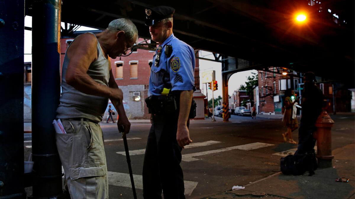 Dave Parke, a transit police sergeant for the elevated train line that runs through a neglected area of north Philadelphia that cops call "The Badlands," helps a man trying to get to a bus stop.