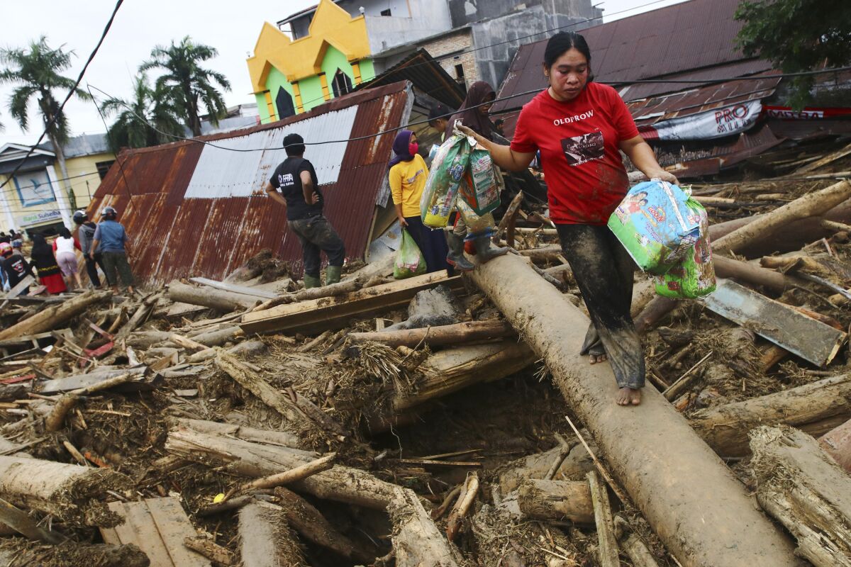People walk on debris at an area affected by flash flood in Masamba, South Sulawesi province, Indonesia, Wednesday, July 15, 2020. Rescuers on Wednesday were searching for missing people after heavy rains in Indonesia's South Sulawesi province swelled rivers and send floodwaters, mud and debris across roads and into thousands of homes. (AP Photo/Khaizuran Muchtamir)