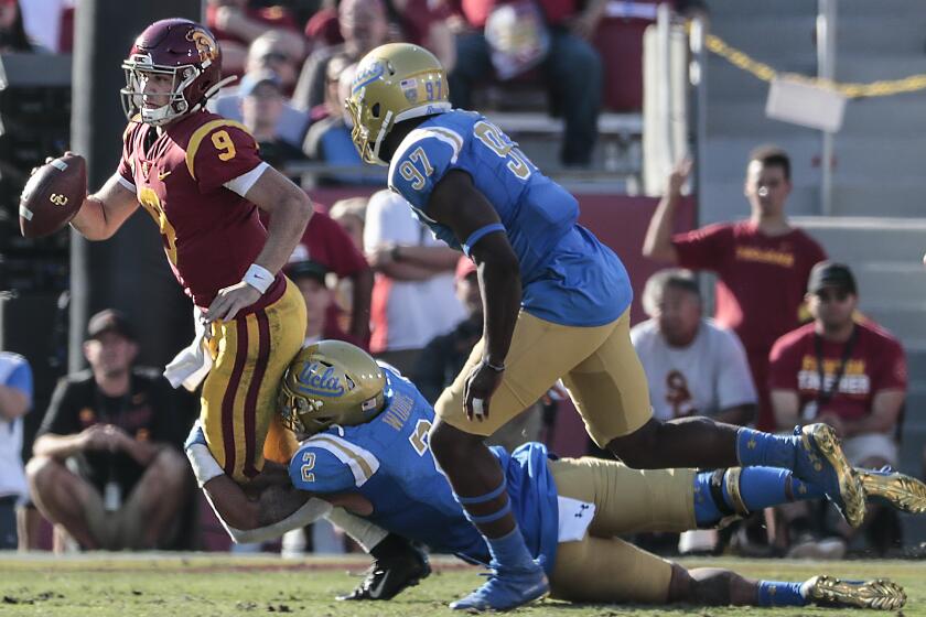 LOS ANGELES, CA, SATURDAY, NOVEMBER 23, 2019 - UCLA Bruins linebacker Josh Woods (2) tackles USC Trojans quarterback Kedon Slovis (9) during a fourth quarter drive at the Coliseum. (Robert Gauthier/Los Angeles Times)