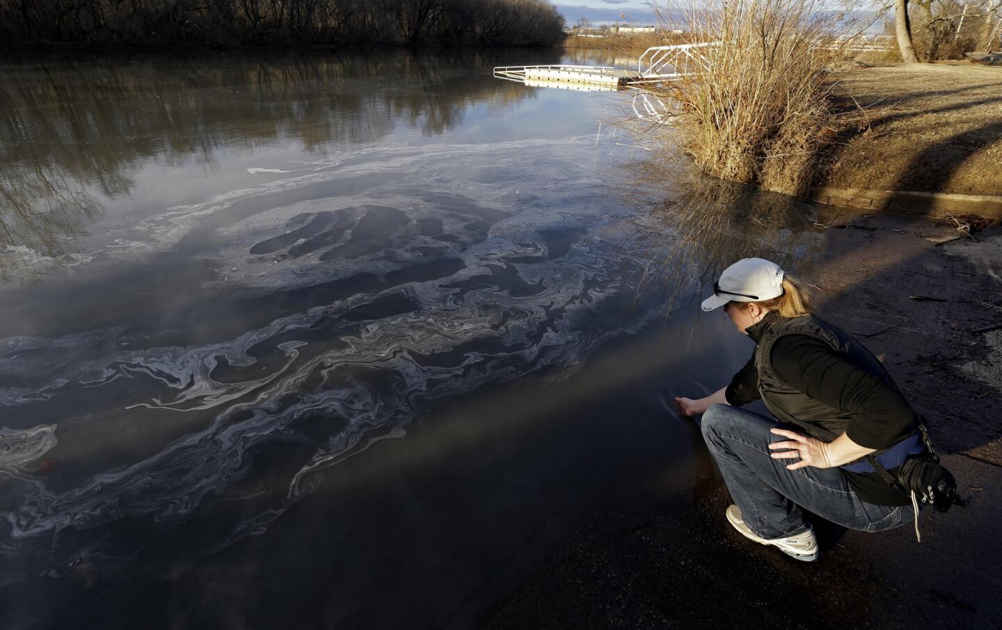 Amy Adams, North Carolina campaign coordinator with Appalachian Voices, dips her hand into the Dan River in Danville, Va., on Feb. 5 as signs of coal ash appear in the river. Duke Energy estimates that up to 82,000 tons of ash have been released from a break in a 48-inch storm water pipe at the Dan River Power Plant in Eden, N.C.