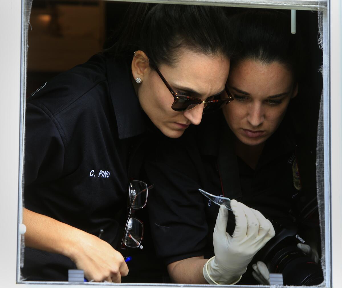 Christina Pino, left, and Gabrielle Wimer look for evidence at a burglary scene.