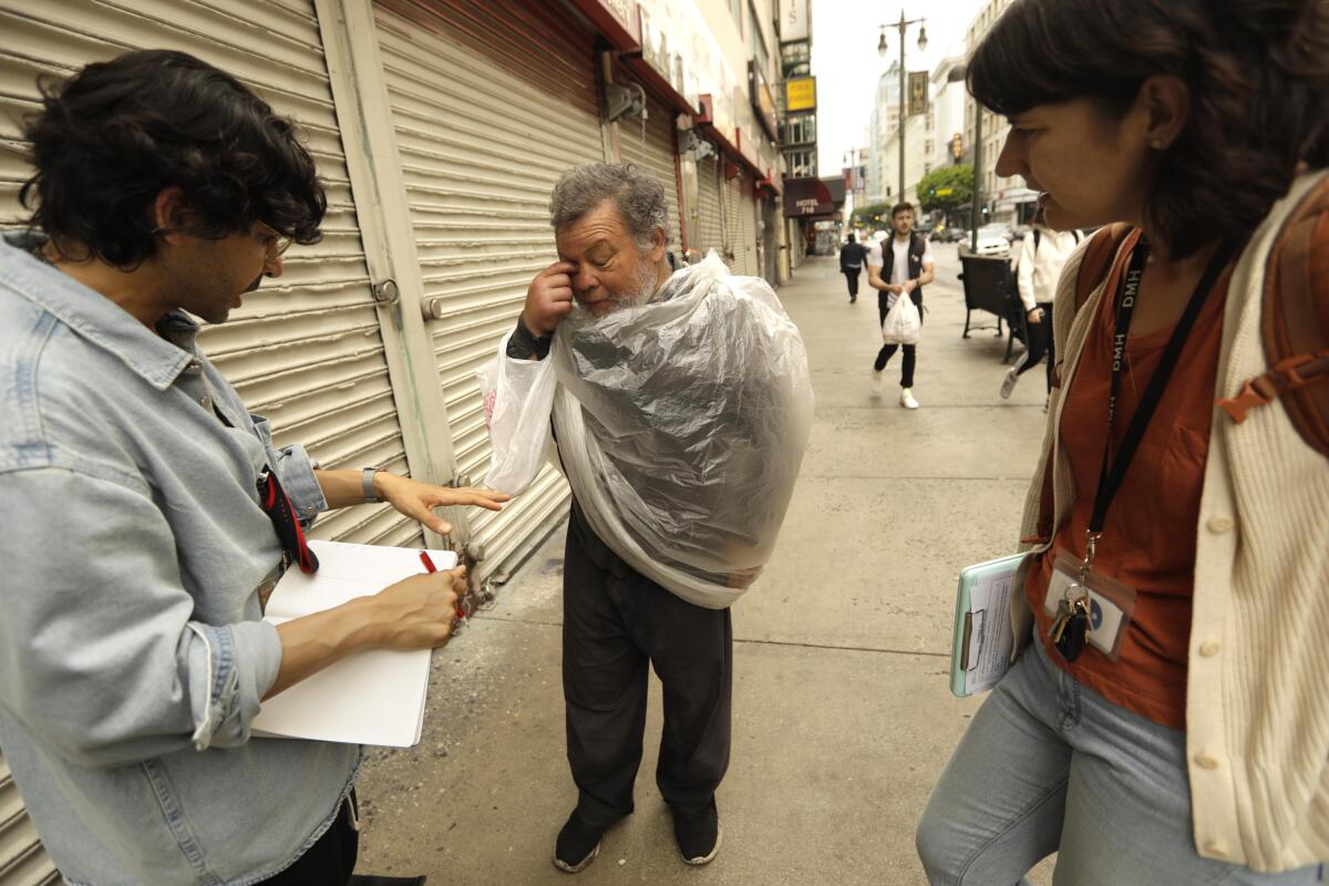 Dr. Shayan Rab, left, and Karla Bennett, right, talk with Juan Luna on a street
